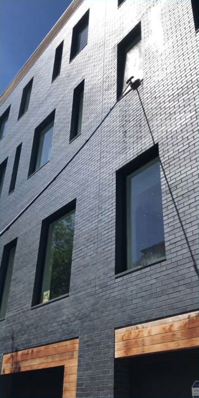 Water-fed pole cleaning upper exterior windows on a Brooklyn building